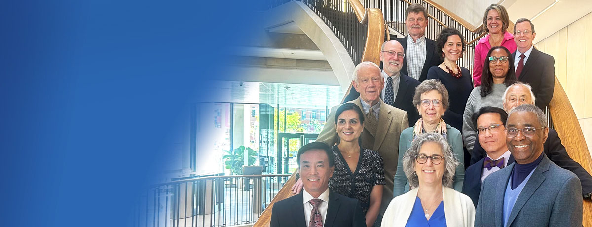 Group of alumni council members standing together smiling on the stairs of Countway Library.